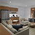 Element Calgary Downtown in Calgary: modern suite with sectional sofa, armchairs, and large wall-mounted TV