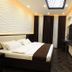 Safir Hotel in Dushanbe guest room with king bed, wall-mounted TV and dark marble accent wall