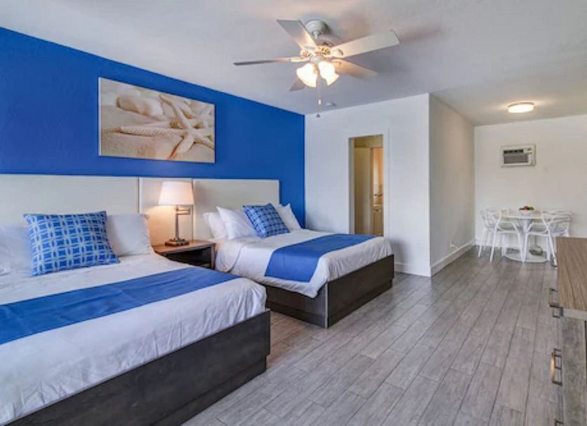 Blue Strawberry by the Sea in Lauderdale-by-the-Sea: room with two beds, blue accent wall and dining nook