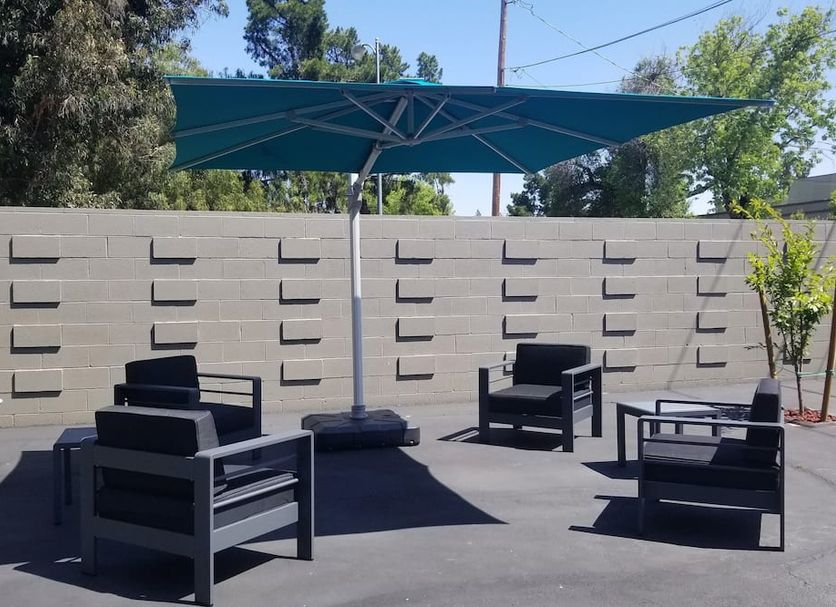 Palo Alto Lodge patio with black lounge chairs, teal umbrella, and concrete privacy wall in Palo Alto