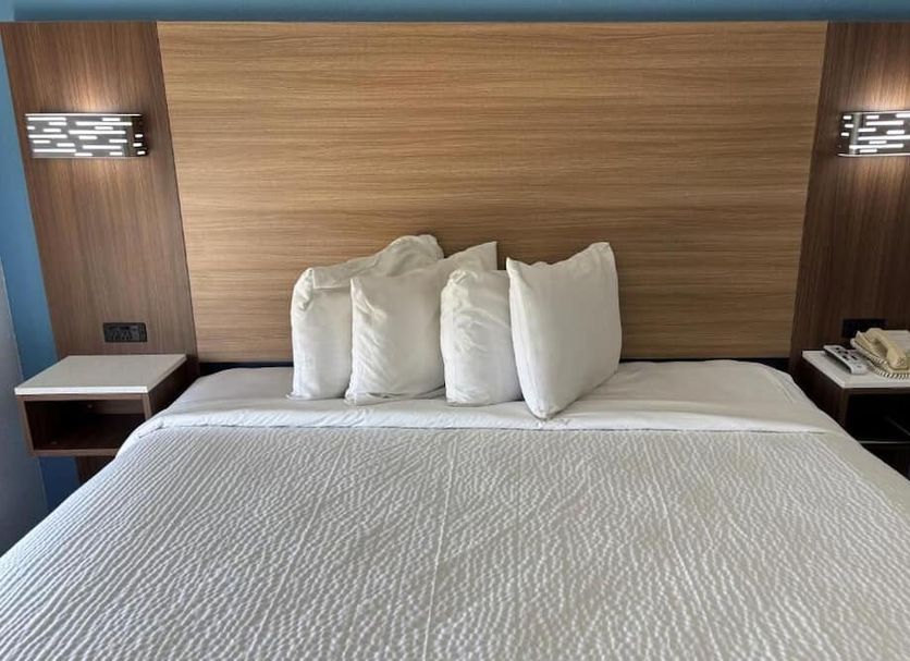 Jacksonville Inn & Suites hotel room with king bed, wood headboard, and bedside lamps in Jacksonville