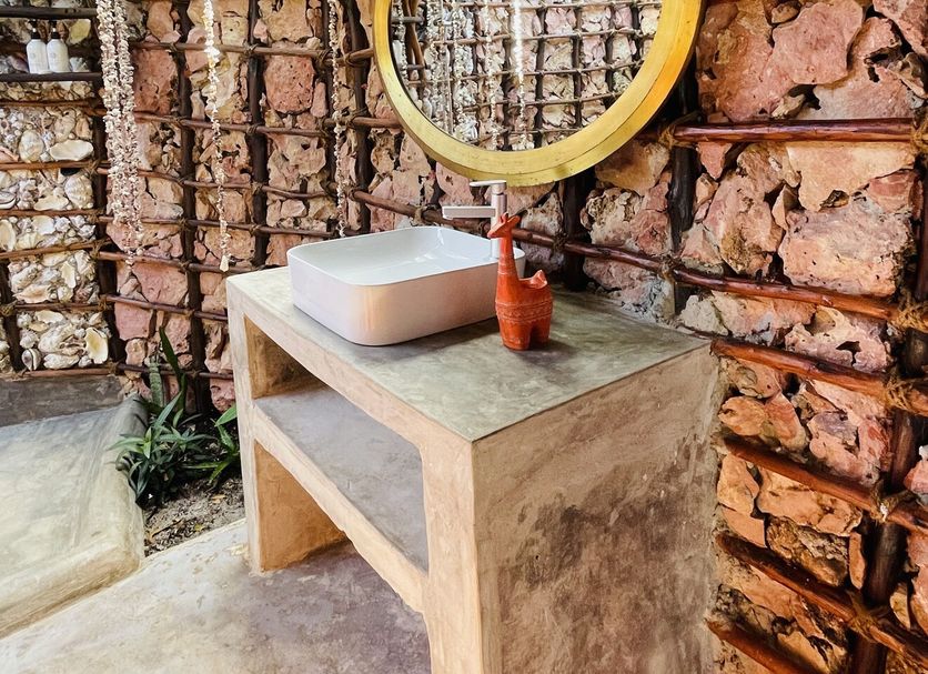 Aya Beach Resort in Kizimkazi bathroom with stone vanity, round mirror and thatched roof