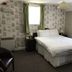 The Embassy Hotel, Great Yarmouth room with double bed, patterned wallpaper and green curtains