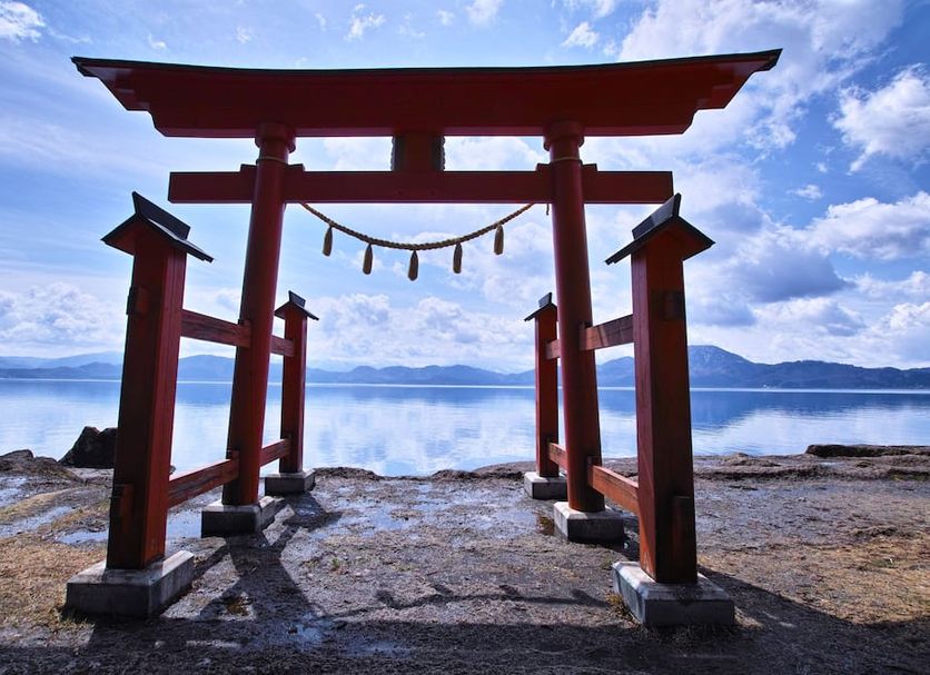 Onsen Yupopo in Semboku: red torii gate overlooking a calm lake with mountains in the distance