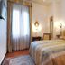 Cà Del Modena Venice room with double bed, wall sconces, and tall window with sheer curtains