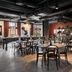 The Winery Hotel, Solna dining area with round tables, black chairs, shelves, and industrial ceiling