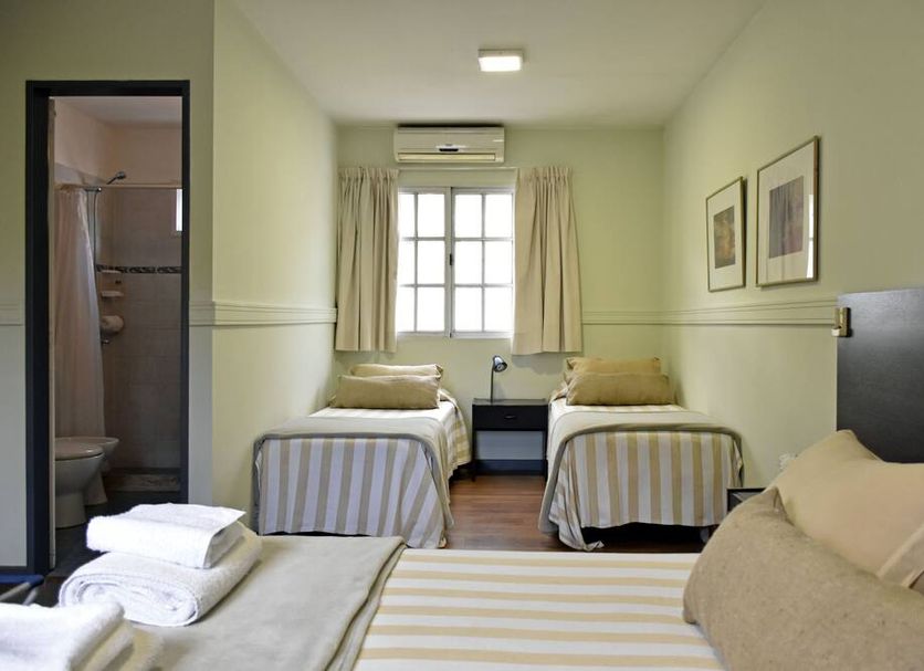 Abril Hotel Boutique in Mendoza guest room with three beds and a small bathroom doorway