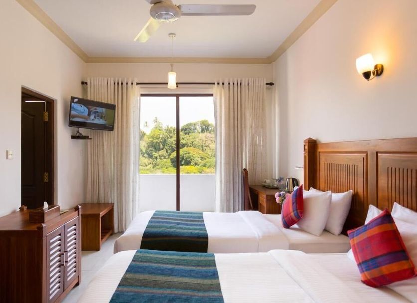 Hotel Yo, Kandy guest room with twin beds, wall-mounted TV, ceiling fan and balcony view of greenery