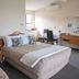 Tuki Tuki Motel Waipukurau room with two beds, desk, mirror, and armchair