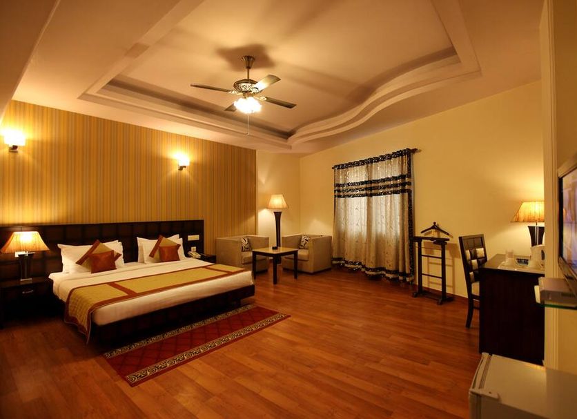Hotel Waves, Delhi Airport room in New Delhi with king bed, wooden floor, ceiling fan and seating area