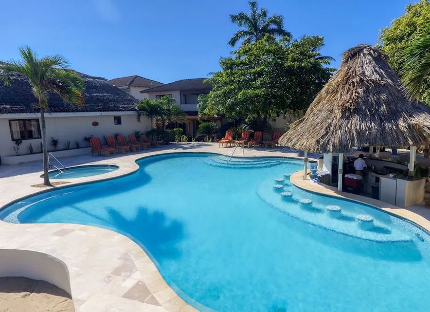 The Colonial at Jaguar Reef in Hopkins: tropical pool with thatched swim-up bar and palm trees