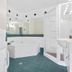 Asure Prince Motor Lodge bathroom in Taupo with corner bathtub, shower, sink and teal tiled floor.