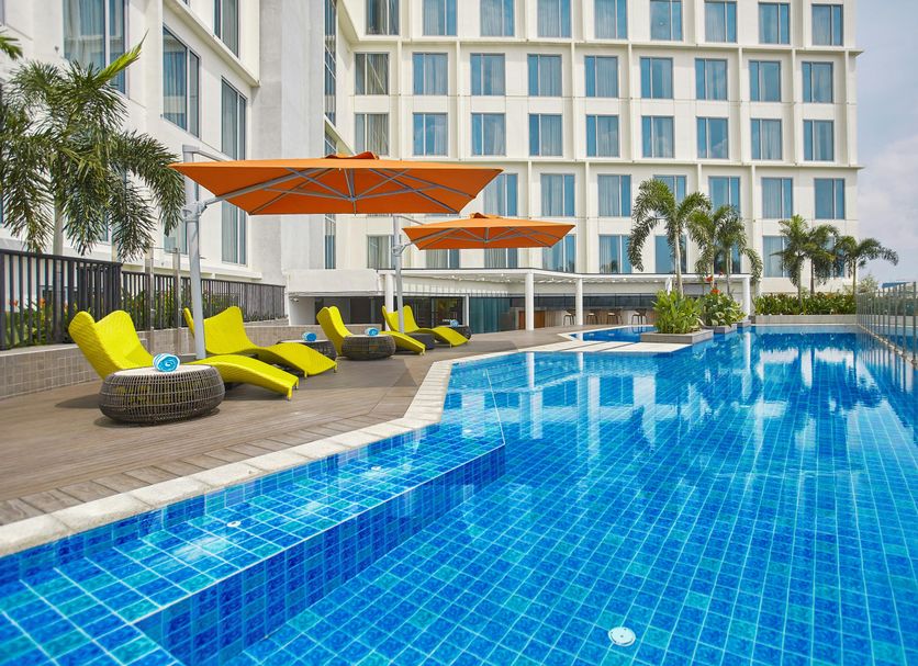 Kingsford Hotel Manila Bay in Manila with a blue pool, orange umbrellas, and lounge chairs