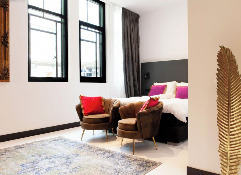 Boutique Hotel De Salon, The Hague guest room with bed, armchairs, large windows and gold wall leaf decor