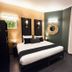 Hotel Peyris Opera in Paris guest room with king bed, dark wood floors, wall sconces and French doors