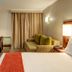 StayEasy Pretoria room with bed, desk, chair, sofa, and curtained window in Pretoria