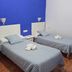 The Dreamers&Co Córdoba room with two single beds, blue accent wall, and tiled floor