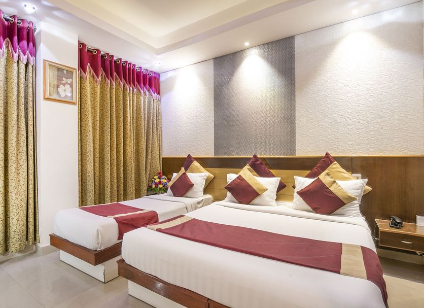 Aishwarya Residency Mysore twin bed room with gold curtains and red accent bedding