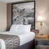 Super 8 by Wyndham Lewistown guest room with a bed, armchair, bedside lamps, and mountain wall art.