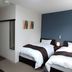 Value the Hotel Ishinomaki guest room with two twin beds, desk, mirror, and blue accent wall