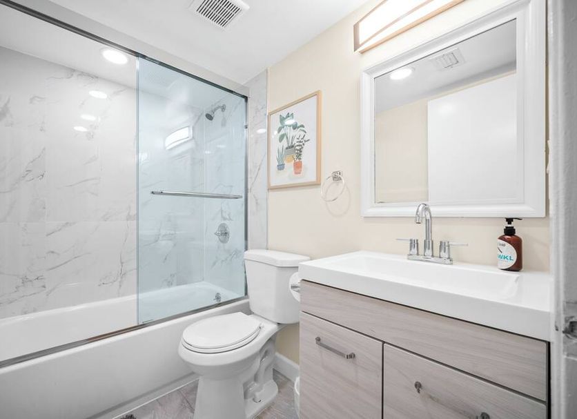 Riverwatch Apartments By Lowkl bathroom in Jensen Beach with glass shower, vanity, toilet and mirror