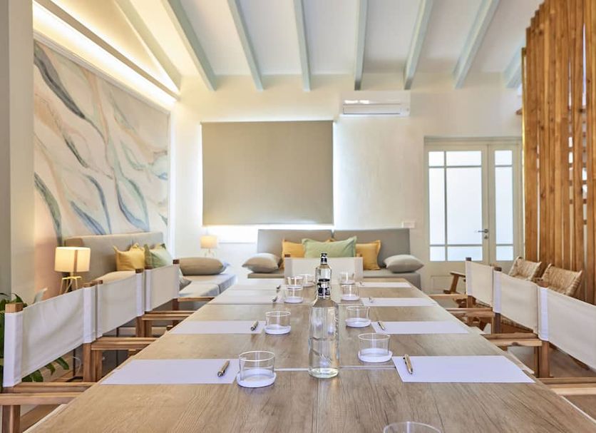 Son Sant Jordi in Pollença: bright hotel dining room with long set table, bench seating and wood slat divider