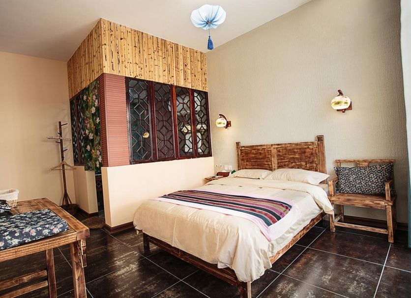 Guilin Lotus Hotel guest room with double bed, patterned chair, and dark tile floor in Guilin