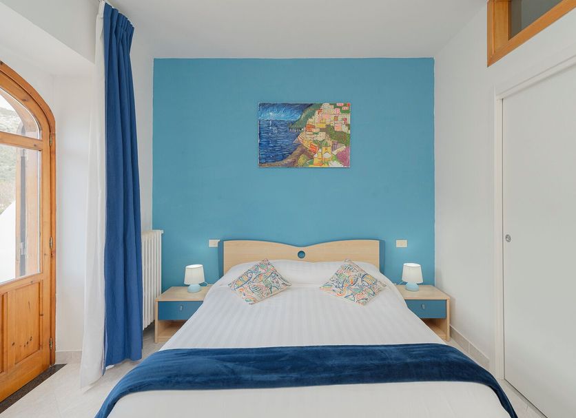 Tra i Monti in Tramonti guest room with double bed, blue accent wall, balcony door and artwork