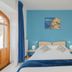Tra i Monti in Tramonti guest room with double bed, blue accent wall, balcony door and artwork