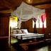Nypa Style Resort Camiguin in Mambajao: rustic bamboo room with canopy bed and mosquito net