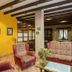 Hotel Villa de Cabrales in Las Arenas lounge with red armchairs, floral sofa, stone wall and wood beams