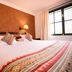 Hotel Raymi Cusco guest room with double bed, bedside lamps, and window with curtains