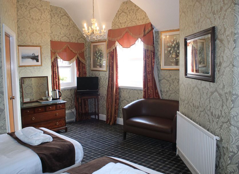 Headlands Hotel Llandudno room with double bed, leather chair, TV, chandelier and patterned wallpaper