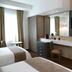 Meson Ejecutivo Guadalajara guest room with twin beds, vanity desk, wall-mounted TV and tall windows