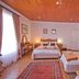 Knysna Manor House room in Knysna with two beds, wooden ceiling, and red rug