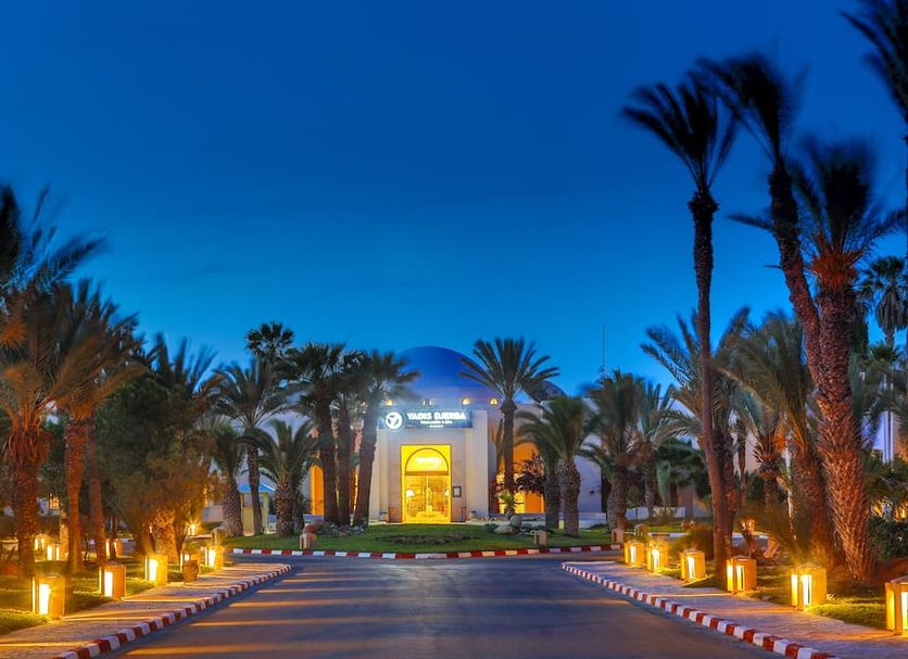Yadis Djerba Golf Thalasso & Spa in Midoun with palm-lined lit driveway at dusk