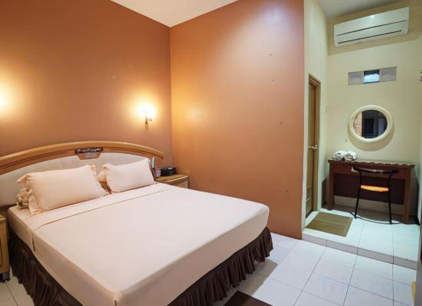 Patria Garden Hotel Blitar room with bed, desk and wall-mounted air conditioner