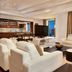 Hilton Dubai The Walk living room with white sofas, TV, open kitchen and city view
