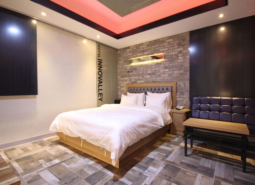 Daegu Innovalley hotel room in Daegu with king bed, stone accent wall, and seating bench