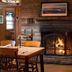 North Creek Lodge at Gore Mountain lounge with lit stone fireplace and wooden dining table in North Creek