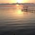 Sunset over the bay at Come Friday Cottages on the Bay in Bacliff, with a pier extending into calm water.