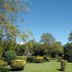 Park Hotel Montrose garden with manicured lawns, shrubs, and mature trees under a clear blue sky