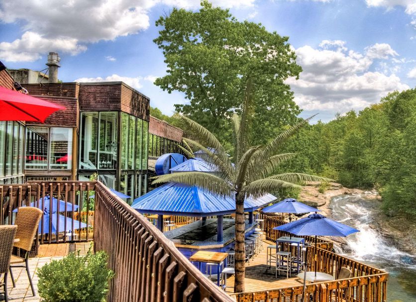The Woodlands Inn in Wilkes-Barre with riverside deck seating, blue umbrellas and a wooded stream view