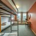 Loft - Hi Eco Hostel Reykjavik dorm room with bunk beds, desk, window and orange accent wall
