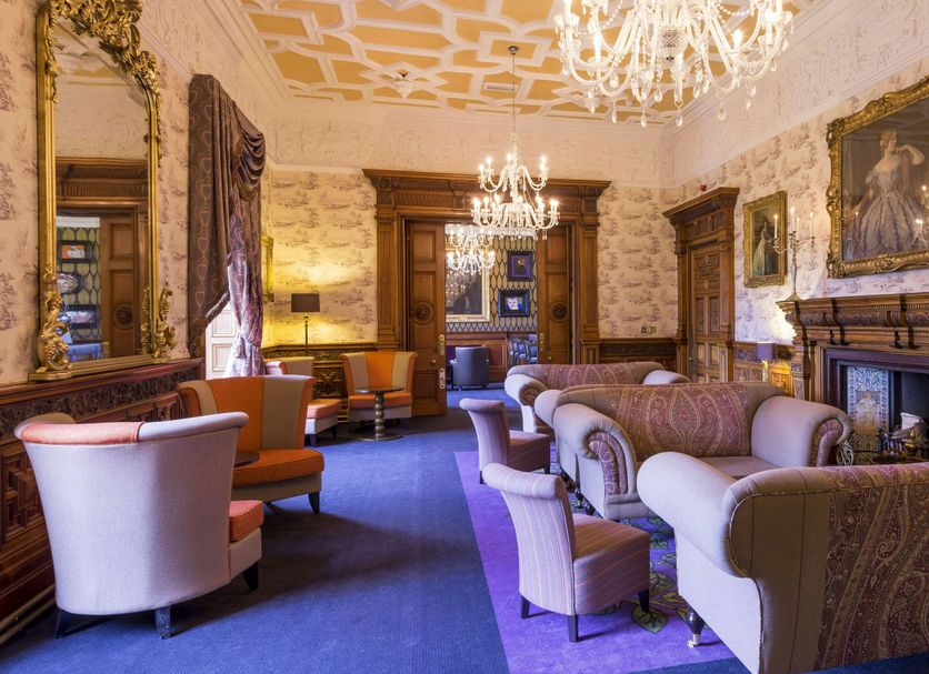 Mercure Aberdeen Ardoe House lounge in Aberdeen with chandeliers, sofas, fireplace and patterned wallpaper
