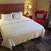 Hampton Inn Garden City guest room with king bed, bedside lamps, and red armchair