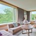 Hakodate-Onuma Prince Hotel in Nanae: bright lounge with large windows, sofa, rocking chair and forest views
