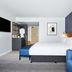 Hyatt Regency London Stratford guest room with king bed, blue sofa and wall-mounted TV in London
