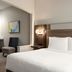 Holiday Inn Express & Suites Edmond guest room with king bed, desk nook, and chair