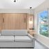 The St Laurent Guest Rooms in Asbury Park: modern room with gray sofa, wood wall bed, and window view